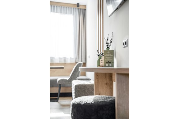 A stylishly furnished room with a wooden table and gray stools. There are plants and an information card on the table. - Marco's Mountain Home - Sölden