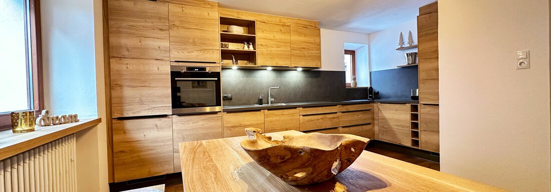 A modern kitchen with wooden cabinets and a large dining table. The room design is bright and inviting. - Mountain Lodge Sölden - Sölden