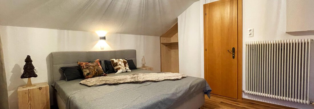 A cozy bedroom with a large bed and a bright ceiling. The wooden floor and modern furniture give the room an inviting atmosphere. - Mountain Lodge Sölden - Sölden