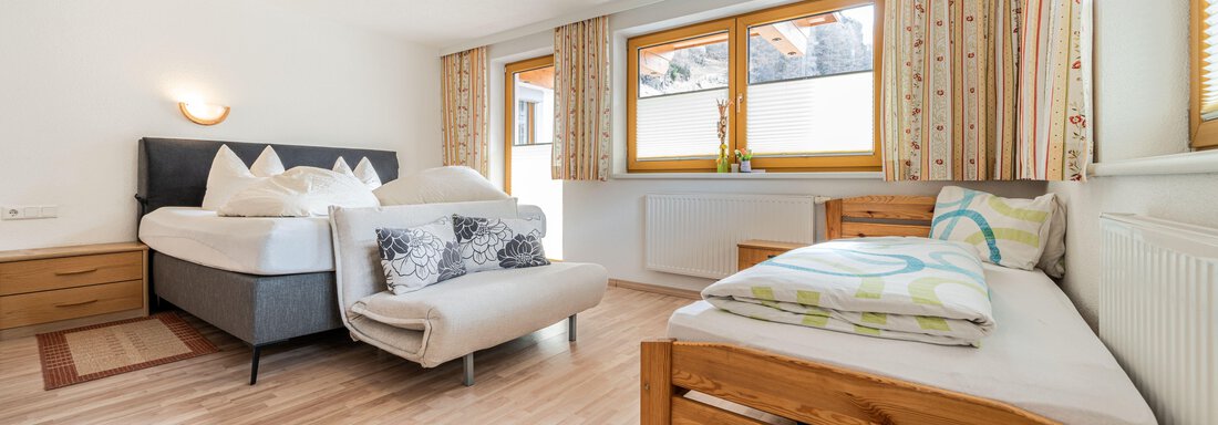 A modern bedroom with two beds and large windows. The room is bright and invitingly decorated. - Pension Birkenheim - Sölden