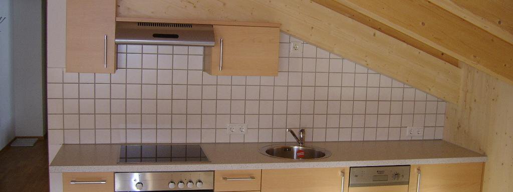 Küchenblock A modern kitchen with wooden cabinets and white tiles. The kitchen is bright and well-designed, ideal for small living. - Pension Birkenheim - Sölden