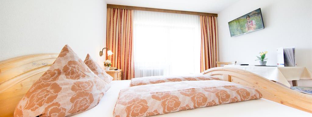 A bright, inviting room with a double bed and decorative cushions. Large windows provide plenty of natural light and a pleasant atmosphere. - Pension Charly - Sölden