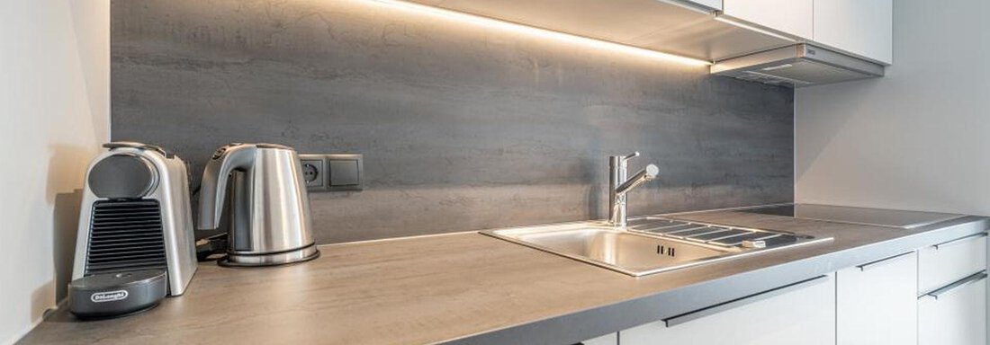 A modern kitchen with a clean work surface and bright lighting. The decor is minimalist and functional. - Pension Miramonte - Sölden