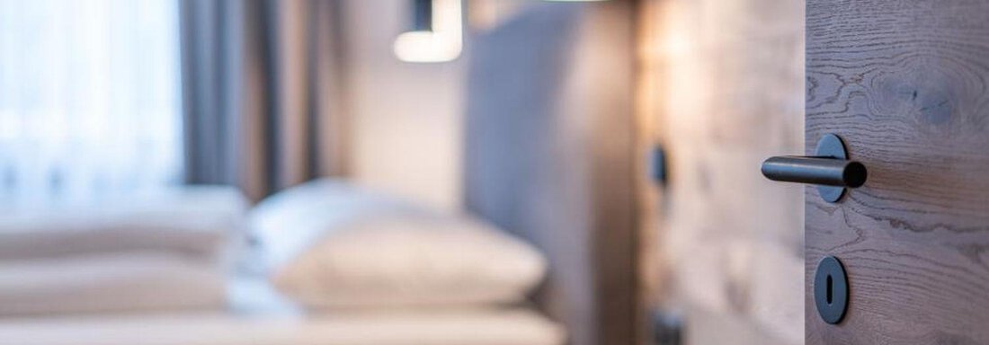 A modern hotel room with two beds and soft lighting. The wooden details and windows create an inviting atmosphere. - Pension Miramonte - Sölden
