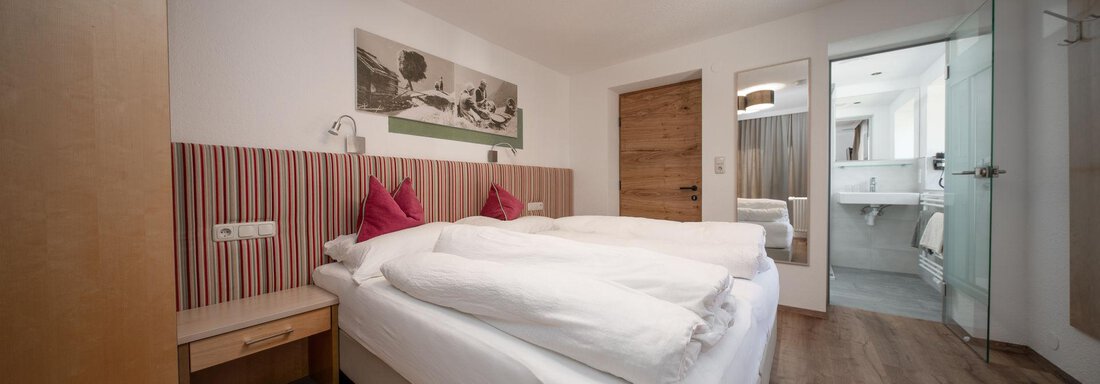 Doppelzimmer | © Andreas Ebermann, Pension Pitze (CC C) A modern bedroom with two beds and a stylish wooden floor. The room has a simple, cozy decor and an adjoining bathroom. - Pension Pitze - Sölden