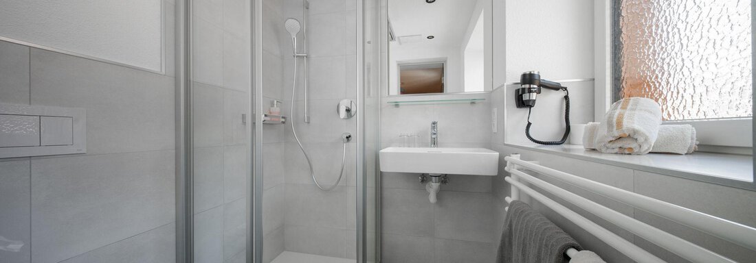 A modern bathroom with a shower and a sink. Bright tiles and natural lighting create a pleasant atmosphere. - Pension Pitze - Sölden