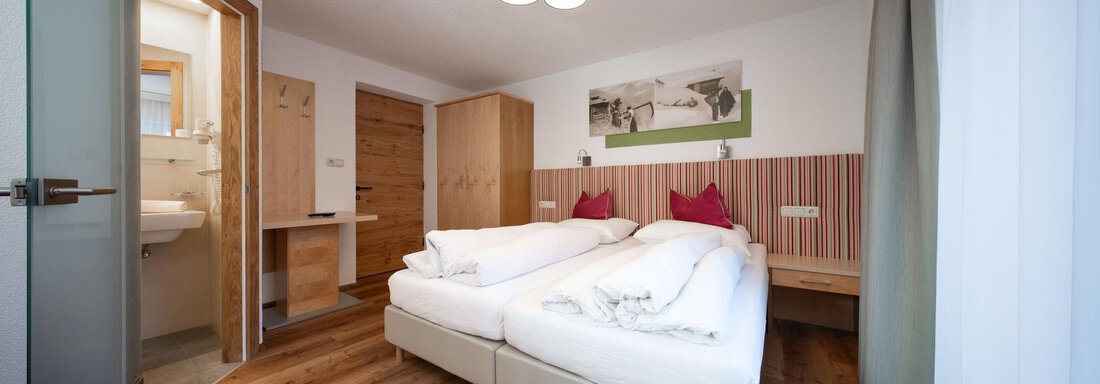 A modern room with two single beds and a pleasant, neutral design. The wooden floors and warm colors create an inviting atmosphere. - Pension Pitze - Sölden