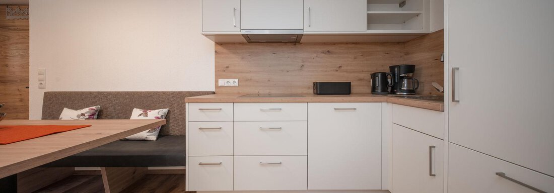 Wohnküche | © Andreas Ebermann, Pension Pitze (CC C) Modern kitchen with white cabinets and wood decor. The dining area is simply and invitingly designed. - Pension Pitze - Sölden