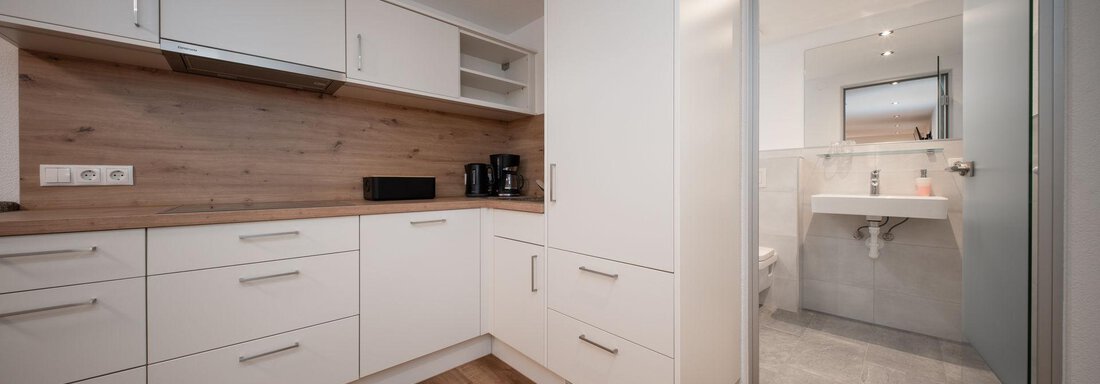 A modern kitchen with white cabinets and wooden details. The space feels bright and welcoming. - Pension Pitze - Sölden