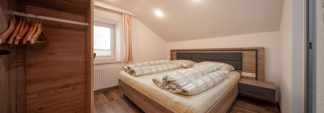 Schlafzimmer | © Andreas Ebermann, Pension Pitze (CC C) A cozy bedroom with a double bed and soft wooden tones. The room has a wardrobe and large windows that provide natural light. - Pension Pitze - Sölden