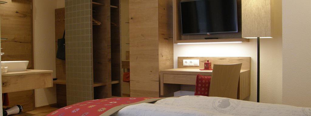A cozy hotel room with wooden interiors, a television, and a nice view of the bed. The bathroom is modern and well-equipped. - Pension Sportalm - Sölden