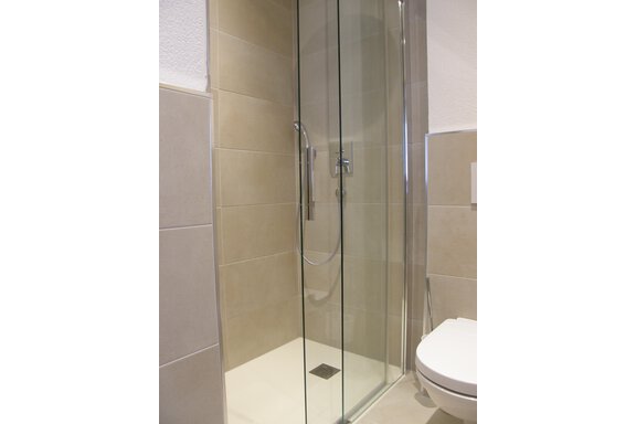 A modern shower with glass separation in a bright bathroom. The walls are designed with beige tiles. - Pension Sportalm - Sölden
