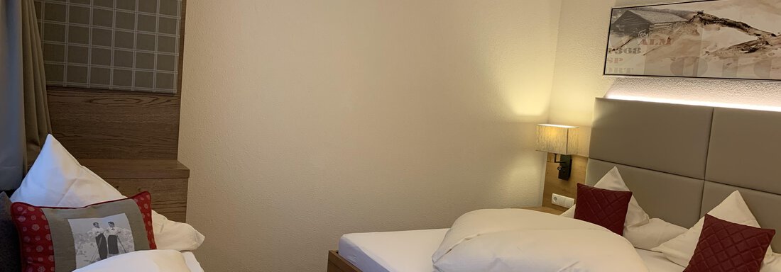 A modern room with two single beds and neutral colors. Cozy pillows and a comfortable atmosphere create an inviting space. - Pension Sportalm - Sölden