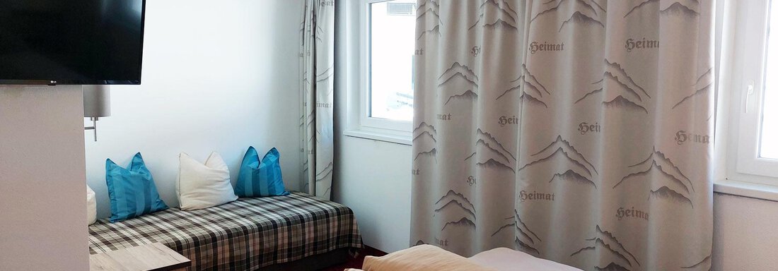 A cozy hotel room with two beds and a seating area. Large windows provide plenty of daylight and a pleasant atmosphere. - Pension "Zur alten Mühle" - Sölden