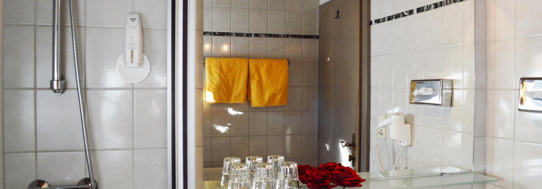 A modern bathroom with a shower area and a sink. Towels and glasses are neatly arranged. - Pension "Zur alten Mühle" - Sölden