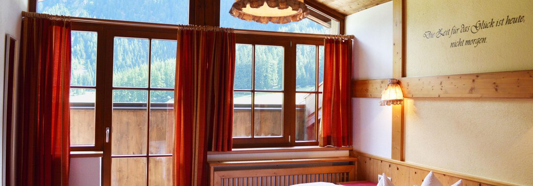 Doppelzimmer mit Balkon | © Carmen Waldhart A cozy bedroom with two beds and a wooden ceiling. Large windows offer a view of nature and let in plenty of light. - Pension "Zur alten Mühle" - Sölden