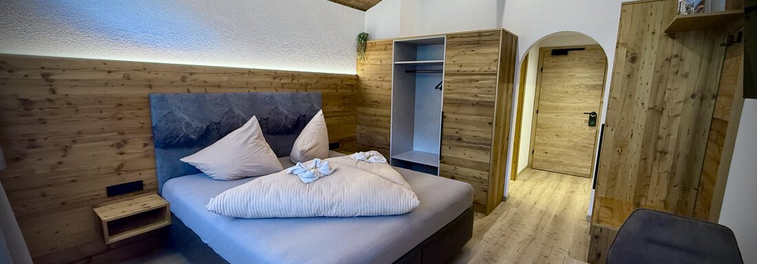 IMG_0108 A modern bedroom with wooden walls and a comfortable bed. The room is bright and designed to be cozy. - Pension "Zur alten Mühle" - Sölden