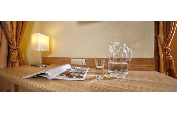 An elegant table with a lamp, a glass of water, and a jug. A magazine is lying on the surface. - Residenz Allegra - Sölden