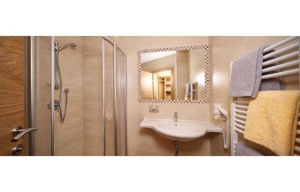 A modern bathroom with a shower, a sink, and a large mirror. Towels in various colors are attached to a towel rack. - Residenz Allegra - Sölden