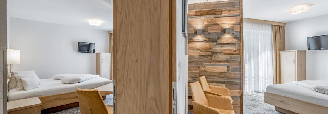 Suite Allegra A modern hotel room with wooden details and stylish furniture. There are two beds, a table, and a cozy seating area. - Residenz Allegra - Sölden