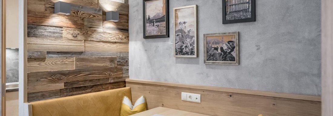 A cozy dining area with wood paneling and soft lighting. Several pictures hang on the wall, conveying a rustic character. - Residenz Allegra - Sölden