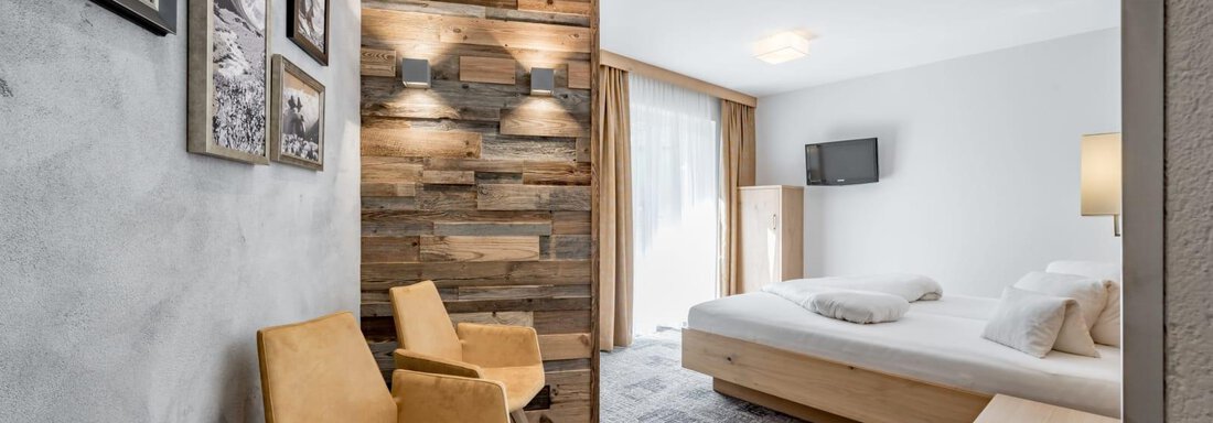 A modern room with wood paneling and comfortable furniture. There are large windows that let in plenty of light. - Residenz Allegra - Sölden