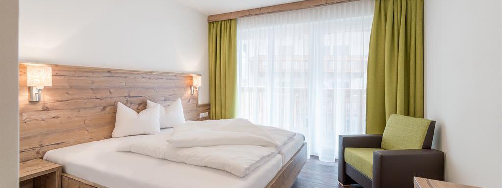 A modern bedroom with a double bed and bright wooden details. The large windows provide plenty of daylight and a cozy atmosphere. - Revmatologická poradna Appt Top 4 - Sölden