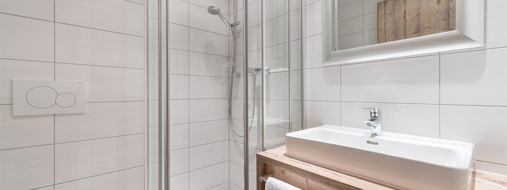 A modern bathroom with a glass shower and a wooden vanity. Bright tiles and large mirrors create an airy atmosphere. - Revmatologická poradna Appt Top 4 - Sölden