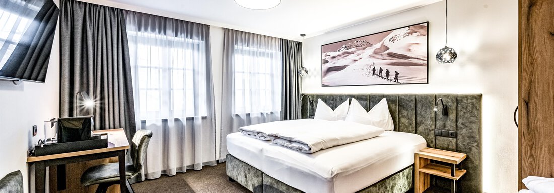 220124_102653-93 A modern hotel room with a double bed, desk, and television. The large windows provide plenty of daylight and a cozy atmosphere. - Sonnalp Residences - Sölden