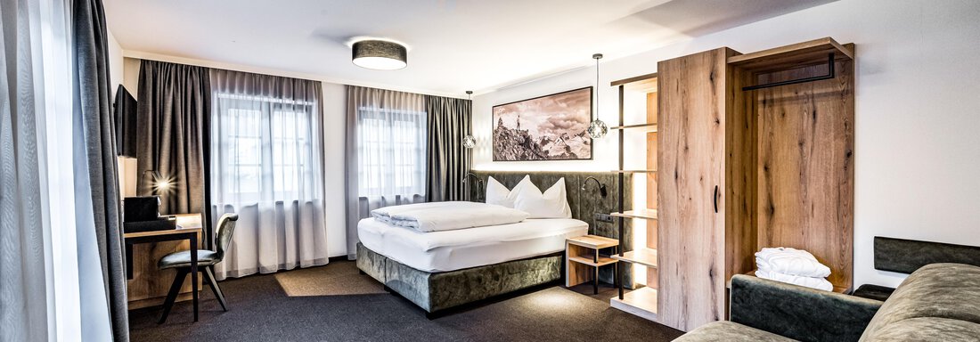 A modern room with a double bed and a cozy seating area. Large windows let in plenty of light and the decor is stylish and inviting. - Sonnalp Residences - Sölden