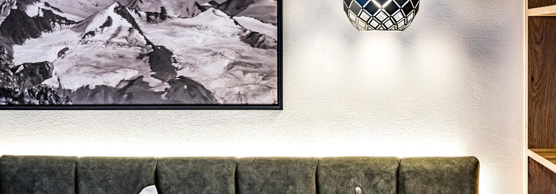 A modern bedroom with a padded headboard and a decorative lampshade. On the wall hangs a black-and-white landscape picture of mountains. - Sonnalp Residences - Sölden
