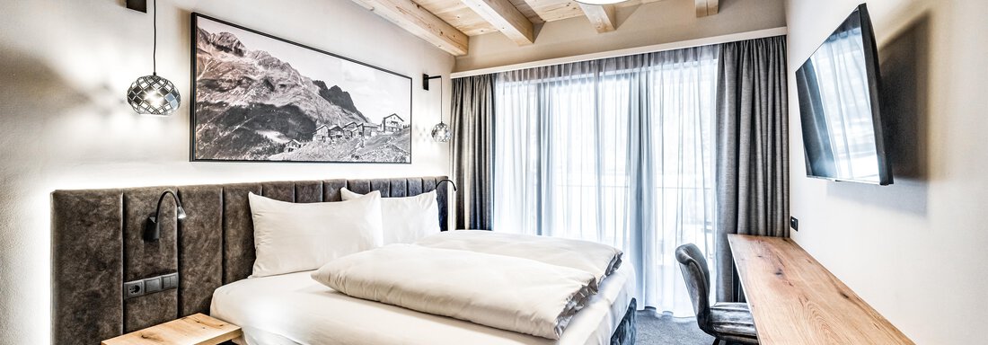 220124_110250-102 A modern bedroom with a double bed and wooden ceiling. Large windows provide plenty of daylight and a view outside. - Sonnalp Residences - Sölden