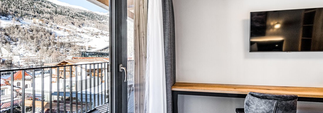 A modern accommodation with a balcony and a view of the surrounding mountains. The decor is bright and cozy, with a television on the wall. - Sonnalp Residences - Sölden