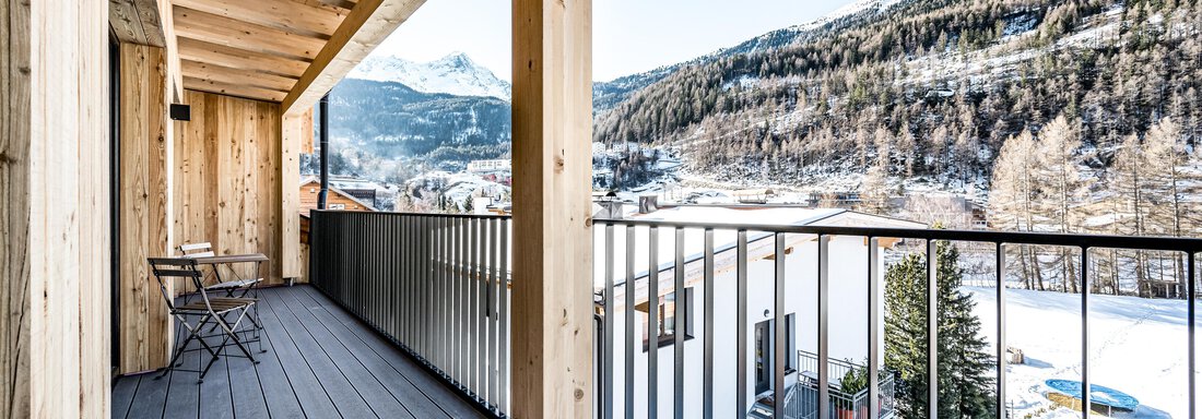 A modern balcony with wooden details and a view of snow-capped mountains. The landscape is calm and inviting. - Sonnalp Residences - Sölden
