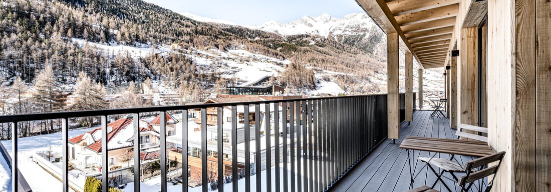 A modern balcony with a view of snow-capped mountains. Two chairs and a table invite you to relax. - Sonnalp Residences - Sölden