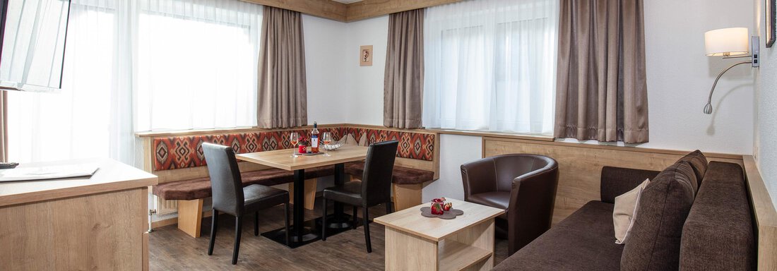 wohngemütlich A cozy living area with a sofa, a table, and chairs. Large windows provide plenty of daylight and an inviting atmosphere. - Sportpension Rubin - Sölden