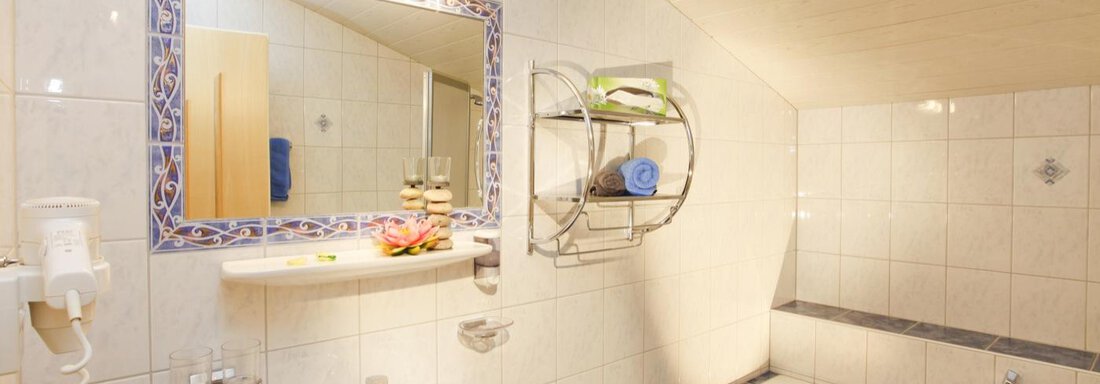 A bright bathroom with white tiles and a large mirror. It features a bathtub and a modern sink installation. - Sportpension Rubin - Sölden
