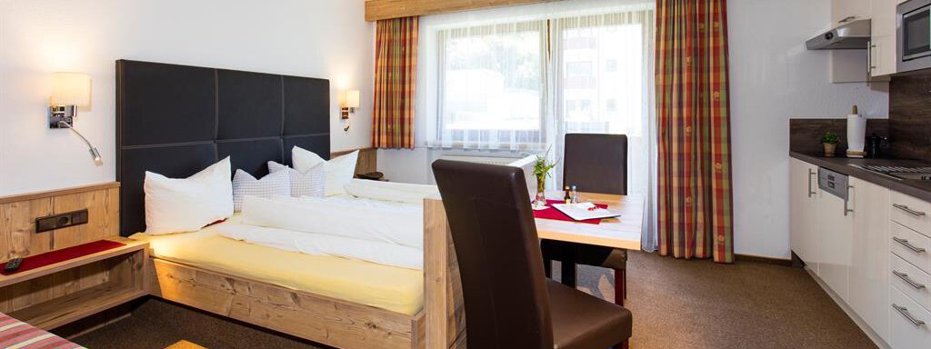 richtig gemütlich A comfortable room with a double bed, a table, and a kitchenette. Large windows let in plenty of daylight and offer a view outside. - Sportpension Rubin - Sölden