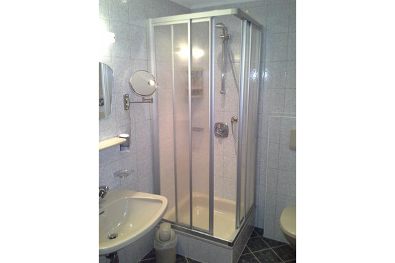 A small bathroom with a glass shower cabin. There is also a sink and a toilet. - Sportpension Rubin - Sölden