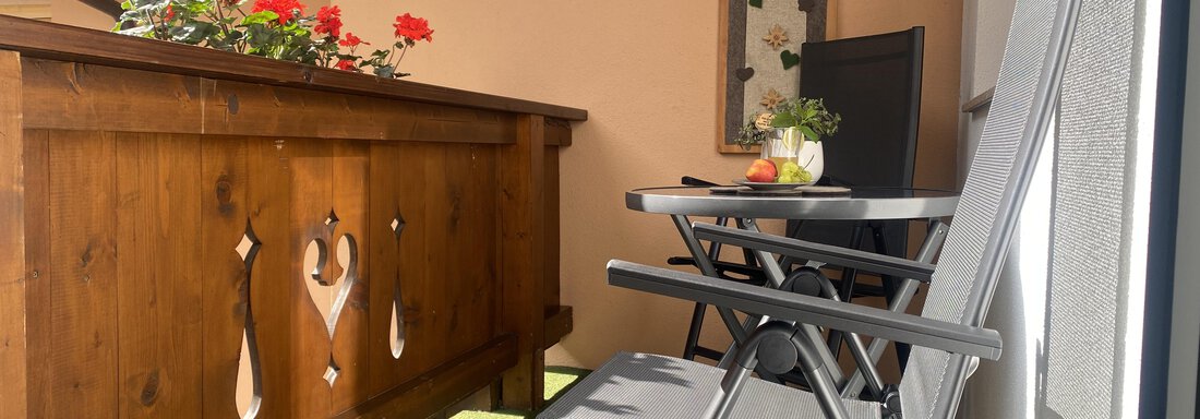 A cozy balcony with blooming geraniums and a small table. Two chairs invite you to relax. - Sportpension Rubin - Sölden