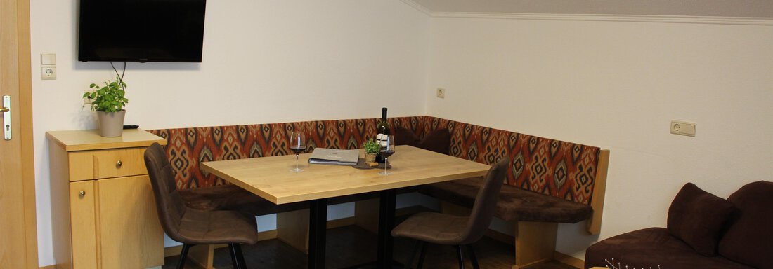 A cozy living area with a dining table and chairs. A television hangs on the wall, and there is a small plant oasis. - Sportpension Rubin - Sölden