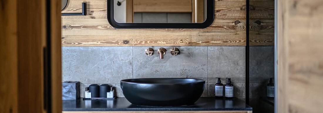 A modern bathroom with wooden paneling and an elegant sink. Towels in various colors are neatly stored. - The Peak Sölden - Sölden