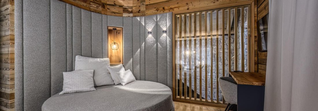 A modern room with a round bed and wooden details. The cozy atmosphere is highlighted by the warm colors and soft lighting. - The Peak Sölden - Sölden