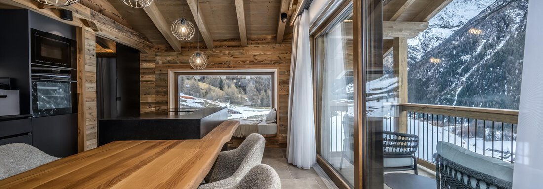 A modern, rustic dining room with wooden ceilings and cozy furniture. Large windows offer a view of snow-covered mountains. - The Peak Sölden - Sölden
