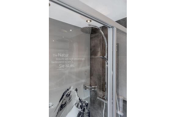 A modern shower room with an elegant rain shower. In the background, there is an inspiring quote about nature. - The Peak Sölden - Sölden