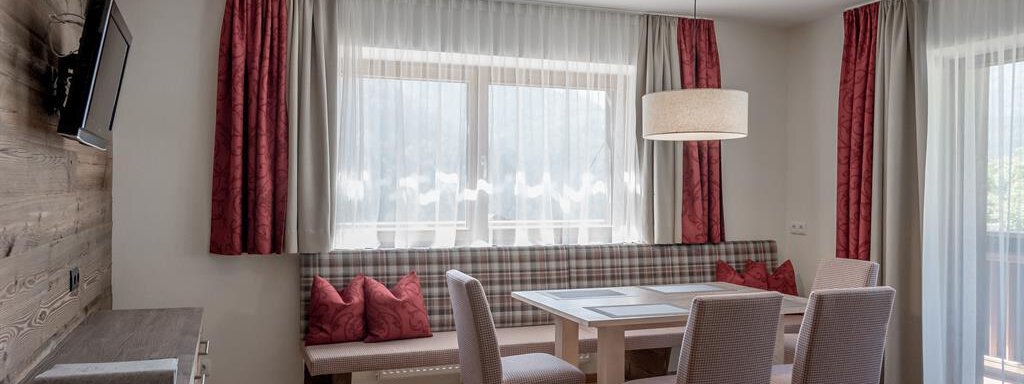 Bright, modern apartment with a dining table and comfortable chairs. Large windows provide plenty of daylight and a cozy atmosphere. - The Peak Sölden - Sölden
