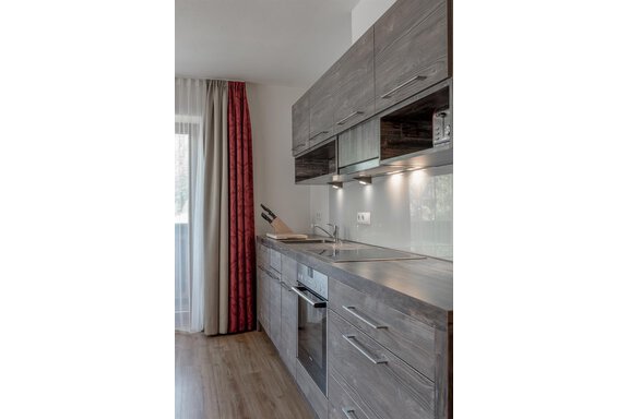A modern kitchen with wood fronts and elegant appliances. Large windows let in plenty of light. - The Peak Sölden - Sölden