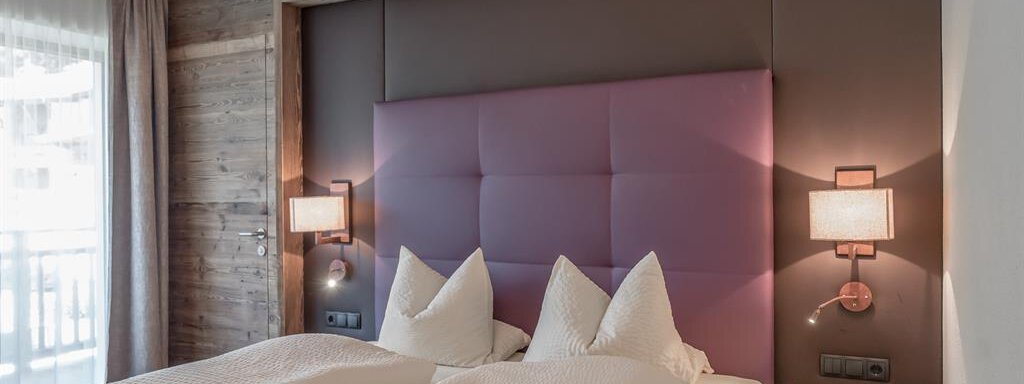 A modern bedroom with two single beds and soft headboards. The warm wood paneling creates a cozy atmosphere. - The Peak Sölden - Sölden