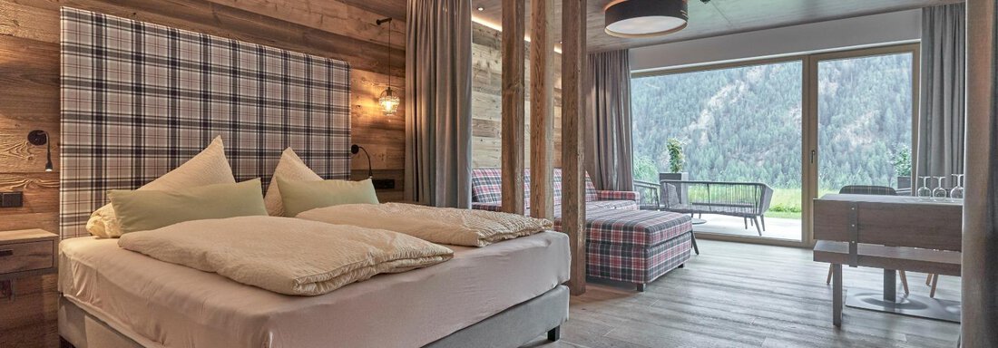 A modern room with wood paneling and a large window that offers a view of the mountains. The bed is cozy and inviting, and the decor is stylish and comfortable. - The Peak Sölden - Sölden