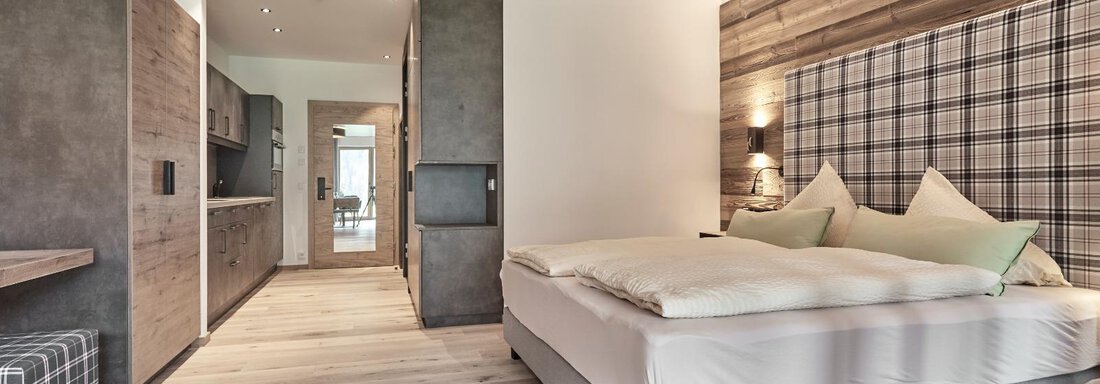 A modern bedroom with a large bed and wooden elements. The walls are elegantly designed, and the room is bright and inviting. - The Peak Sölden - Sölden